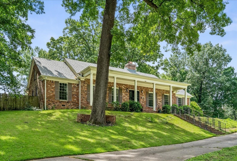 Brick exterior residence featuring a covered front porch with white columns, a pitched roof, and an attached chimney