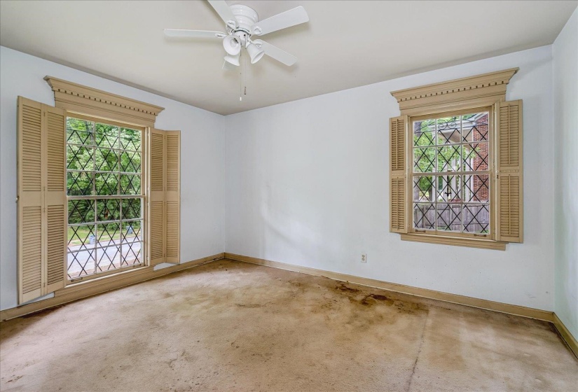 White walls complement two windows featuring decorative grilles and louvered shutters