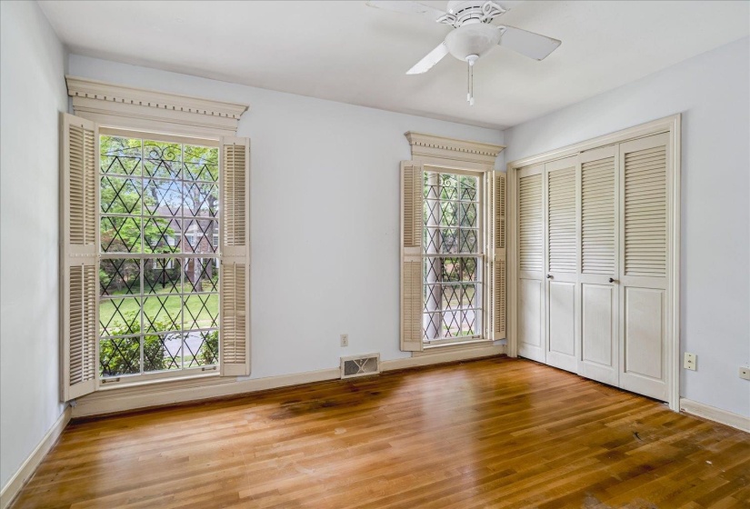 Hardwood flooring complements two large windows featuring decorative muntins and interior louvered shutters