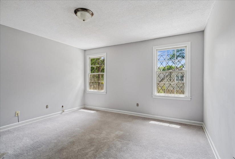 Interior room featuring light gray walls, textured ceiling, and gray carpet flooring