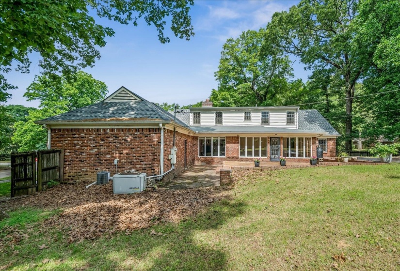Expansive rear exterior featuring a brick facade and a wide lawn