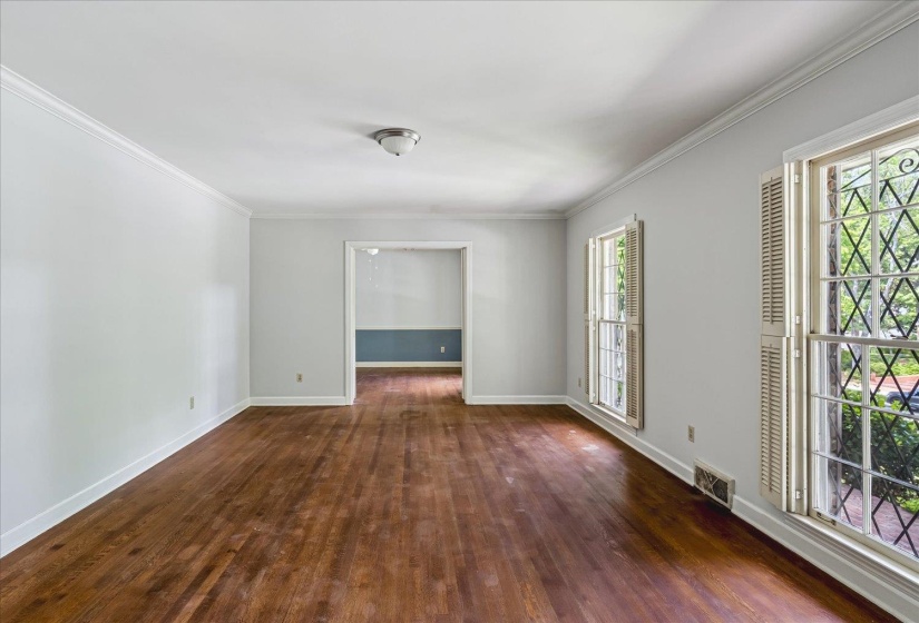Spacious room featuring rich wood-finish flooring, white walls, and elegant crown molding