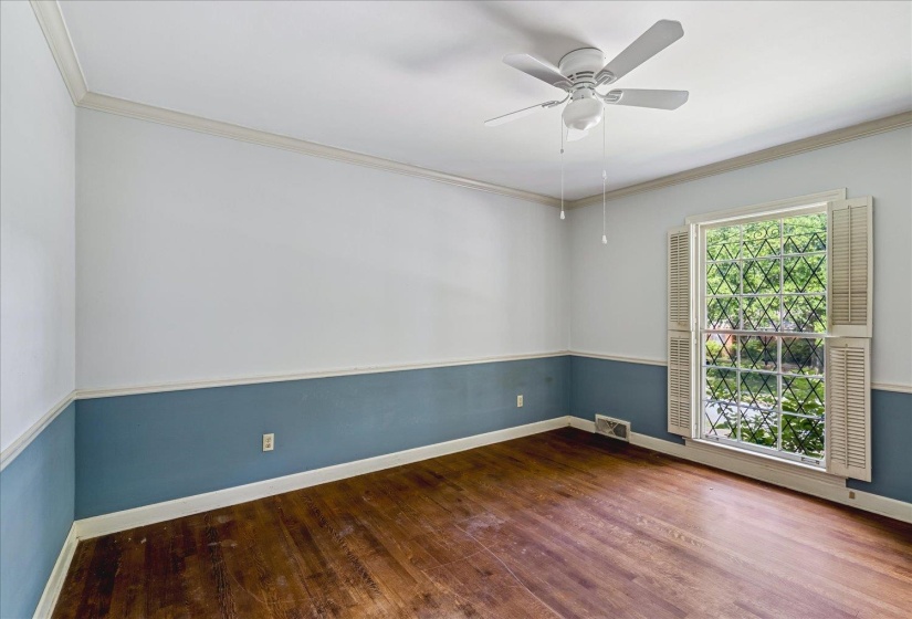 Room featuring wood-finish flooring, two-tone wall treatment with chair rail molding, and a ceiling fan with integrated lighting