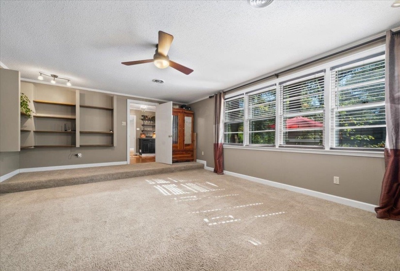 Primary Bedroom featuring a textured ceiling, light carpet, a ceiling fan and plenty of natural light.