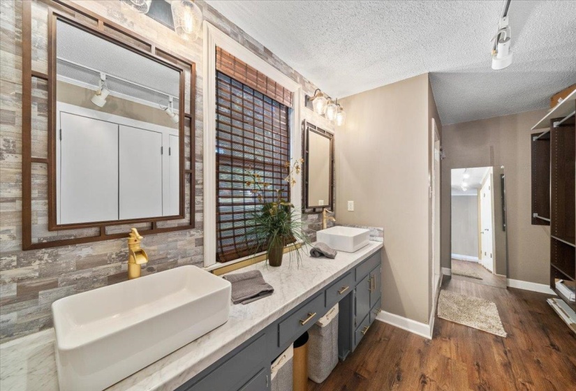 Bathroom featuring double vanity, a textured ceiling, and dark wood-type flooring