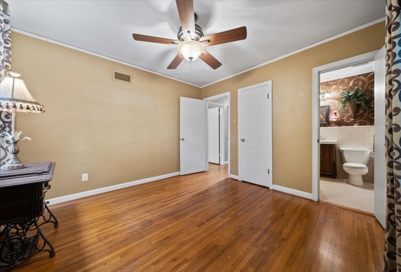 Bedroom featuring ornamental molding, wood finished floors, ceiling fan, and ensuite bathroom