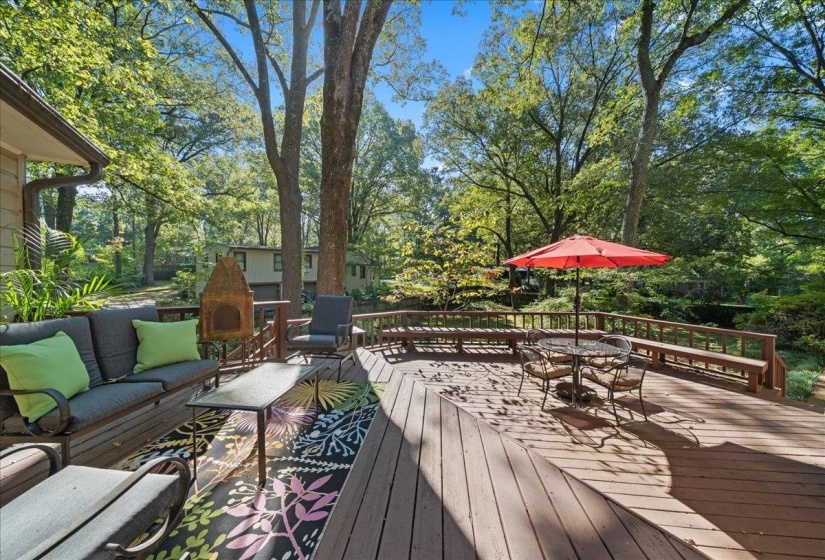 Wooden deck featuring view of scattered trees, outdoor dining area, and an outdoor hangout area