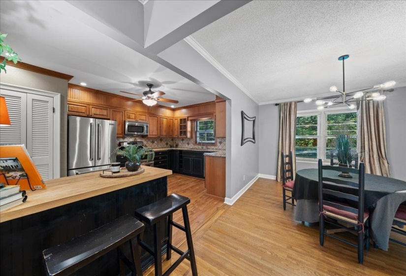Kitchen featuring appliances with stainless steel finishes, ornamental molding, light wood-style floors, brown cabinets and granite counter tops