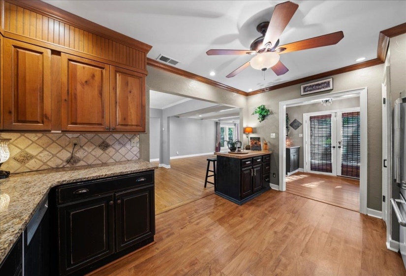 Kitchen featuring a kitchen bar, light granite counters, light wood-type flooring, dark cabinetry, and a ceiling fan
