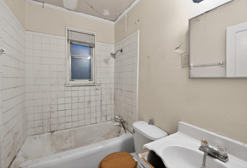 Bathroom featuring a window with blinds, a showerhead, and a vanity with a sink