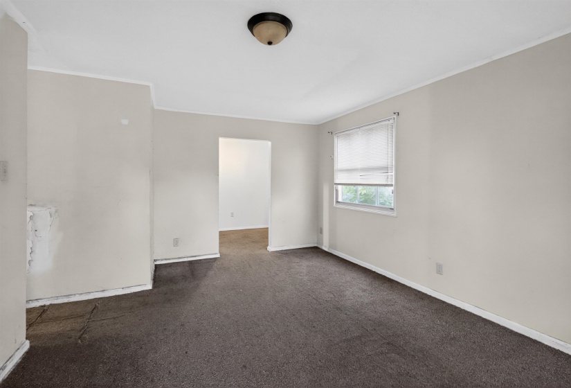 Room featuring neutral-toned walls, dark carpet, a ceiling-mounted light fixture, and a window with blinds