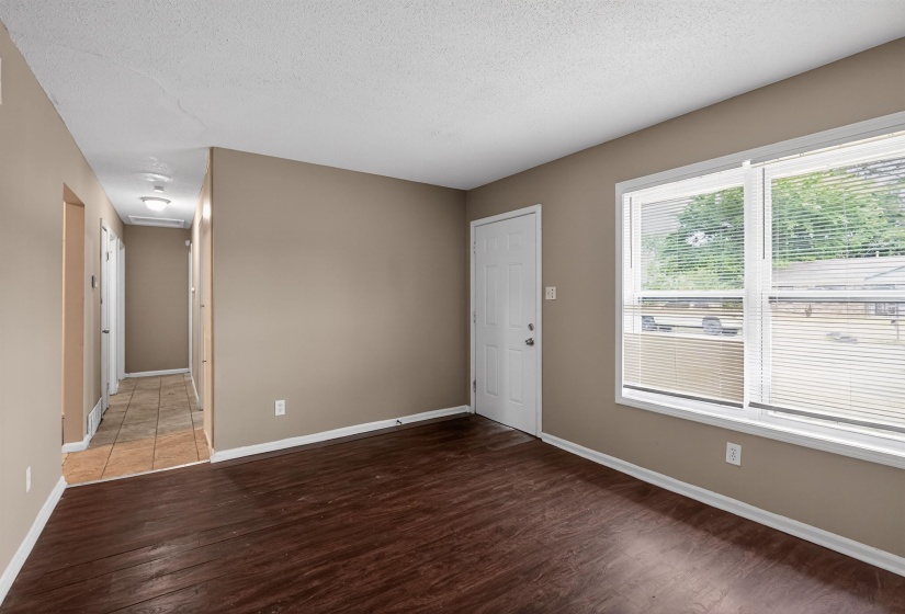 Spacious room with dark wood-finish flooring, neutral-toned walls, and white trim