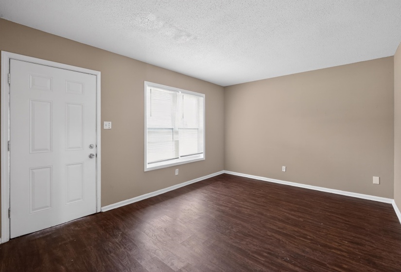 Entry room featuring a paneled door, wood-finish flooring, neutral wall tones, and horizontal blinds