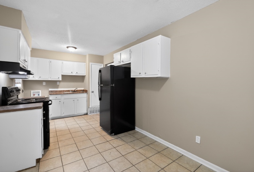 Kitchen featuring white cabinetry, tile flooring, a black refrigerator, and a black range with an overhead vent