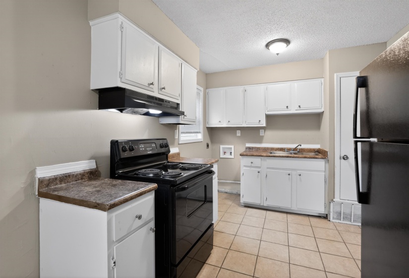 Kitchen featuring white cabinetry, dark countertops, tile flooring, a black range, and a black refrigerator