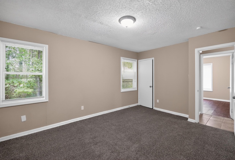 Spacious room featuring neutral tone walls, dark carpet flooring, and white trim