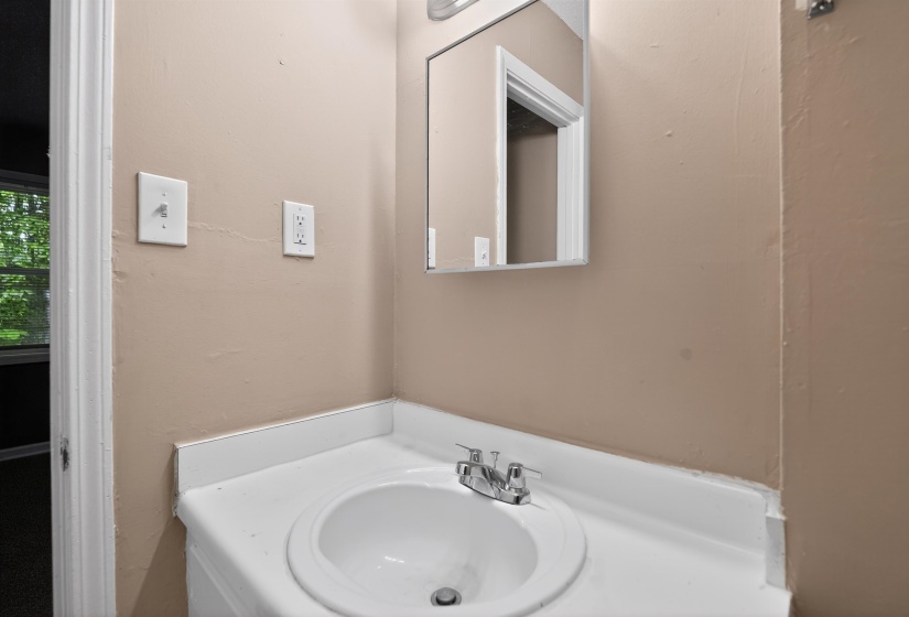 White integrated sink and countertop with a chrome two-handle faucet and a framed wall mirror