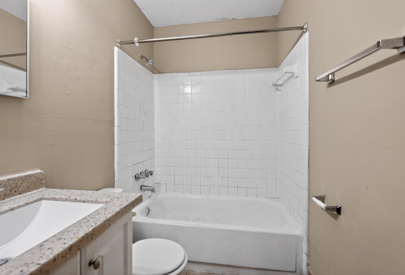 Bathroom featuring a shower-tub combination with white subway tile surround, chrome fixtures, and a curved shower rod