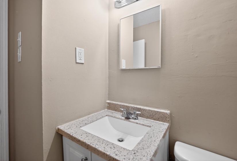 Vanity featuring a speckled countertop, integrated sink, and chrome faucet
