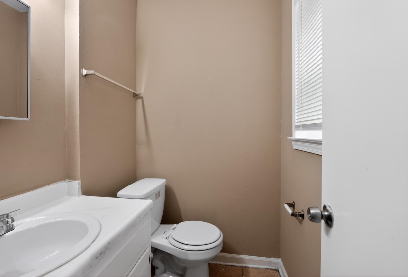 Bathroom featuring a white vanity with integrated sink, chrome faucet, white toilet, and window with blinds