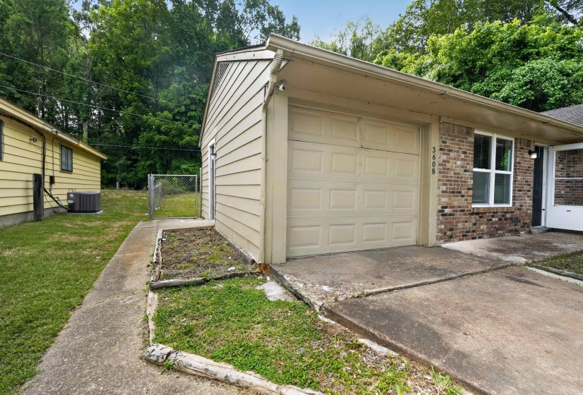 Brick and siding exterior featuring an attached garage with a concrete driveway, a side entry door, and a privacy-fenced yard