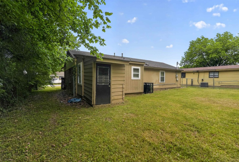 Expansive backyard area featuring a manicured lawn, exterior siding, and mature perimeter trees