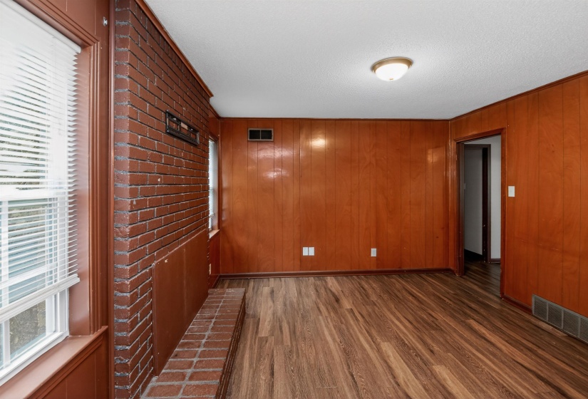 Spacious interior featuring wood-finish flooring, wood paneling, and a brick accent wall with a hearth
