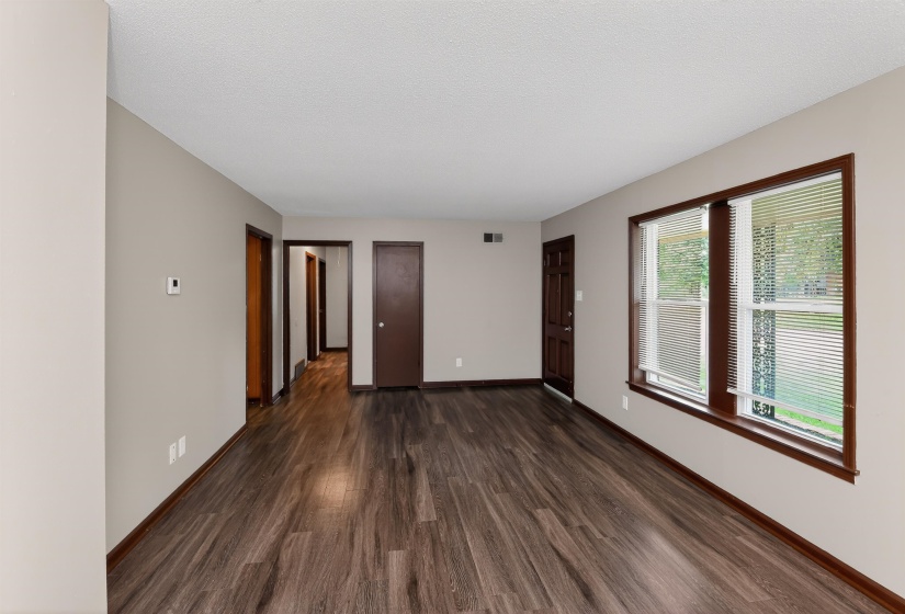 Spacious interior with dark wood-finish flooring, light neutral-toned walls, and dark trim