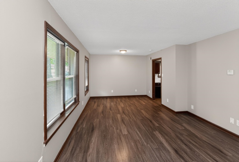 Spacious room featuring wood-finish flooring, neutral wall tones, multiple windows with blinds, and recessed lighting