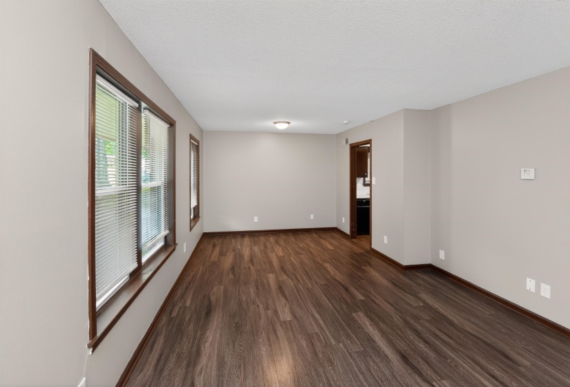 Spacious room with dark wood-finish flooring, neutral wall paint, and white textured ceilings