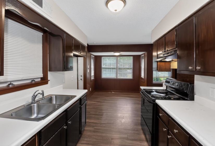 Kitchen featuring dark wood-finish cabinetry, white countertops, and a dual basin stainless steel sink