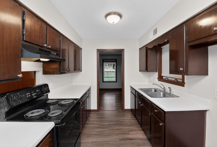 Galley kitchen featuring wood-finish cabinetry, white countertops, and wood-finish flooring