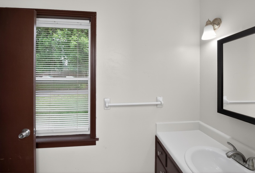 Bathroom vanity with white countertop, integrated sink, and brushed nickel faucet
