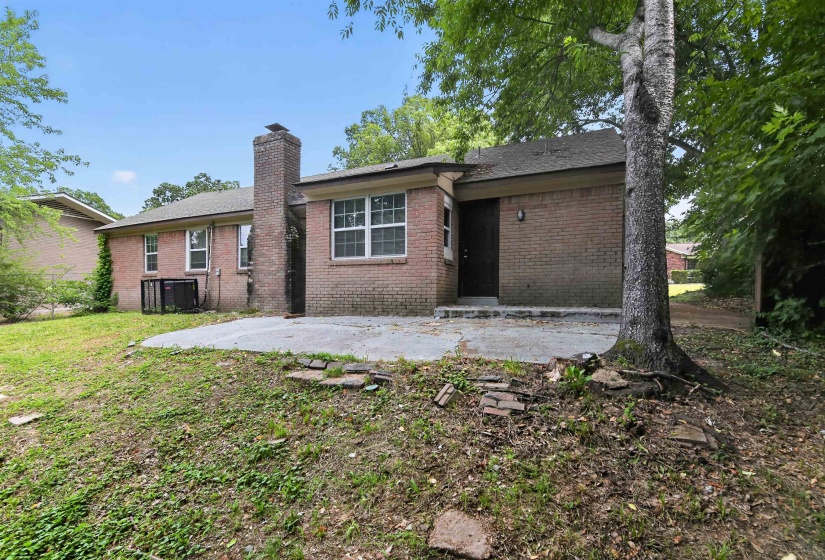 Brick exterior with a prominent brick chimney and a concrete patio