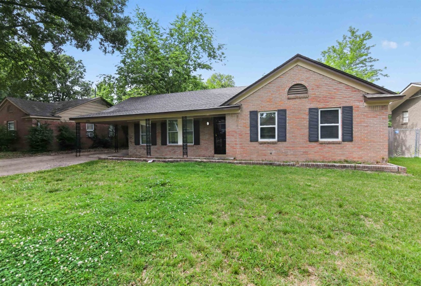 Brick exterior featuring a covered front porch with decorative columns, a gabled roofline, and front-facing windows with dark shutters