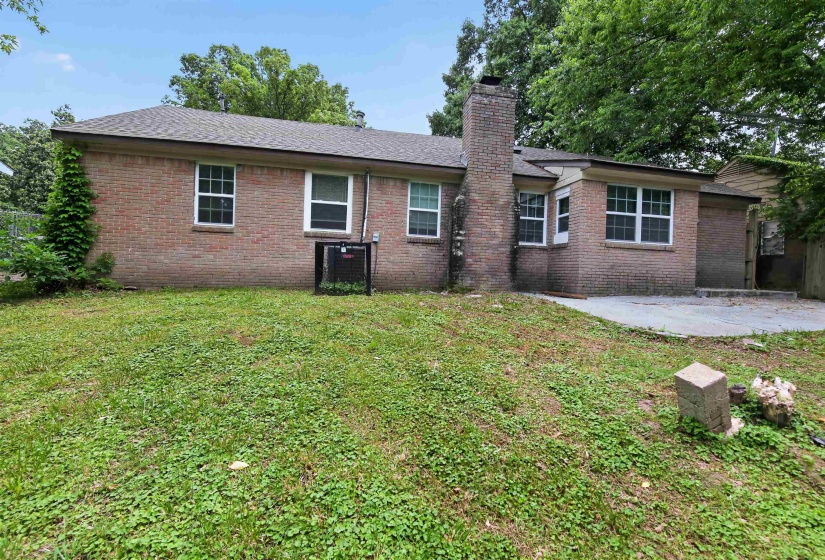 Brick exterior featuring multiple windows and a single chimney