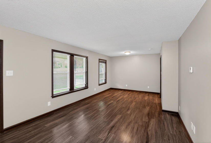 Spacious interior room featuring wood-finish flooring, neutral wall tones, and dark trim details