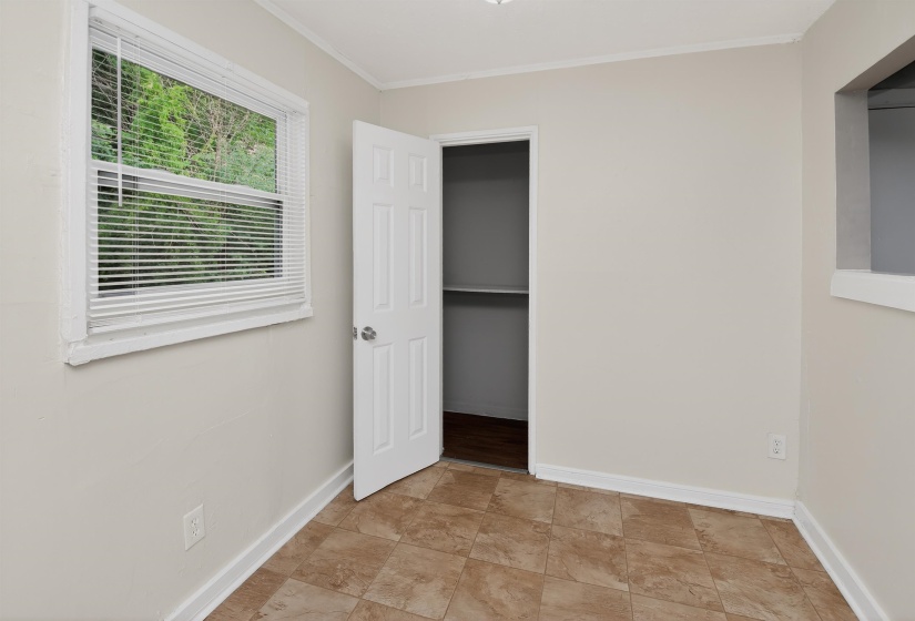 Neutral-toned walls and durable tile flooring define this room, featuring a window with white blinds