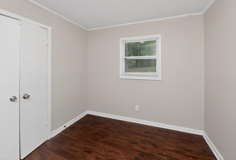 Room featuring wood-finish flooring, neutral wall tones, and white trim