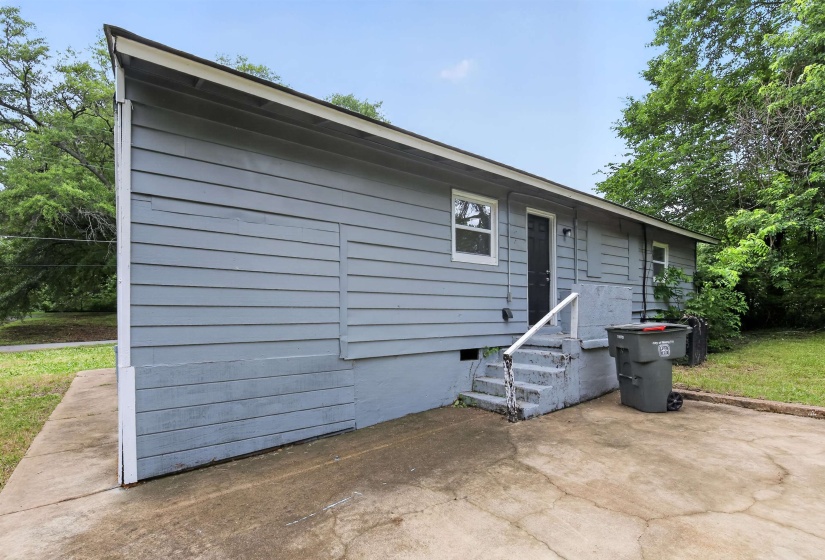 Exterior featuring horizontal siding, white trim, a rear entry door, and concrete steps with a handrail