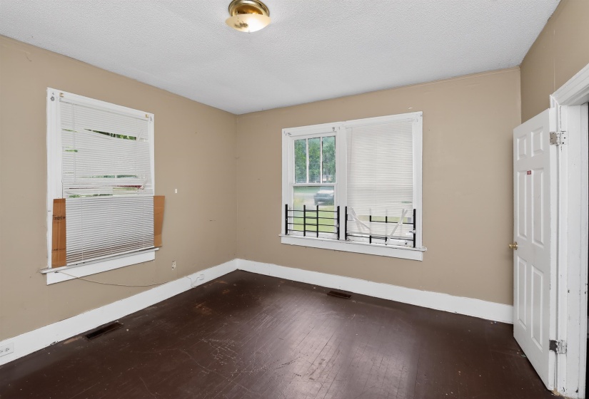 Interior room featuring wood-finish flooring, two windows with white blinds, and a white paneled door