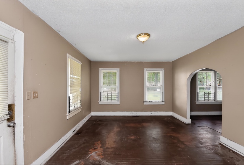 Spacious room with multiple windows, an arched doorway, and a ceiling-mounted light fixture