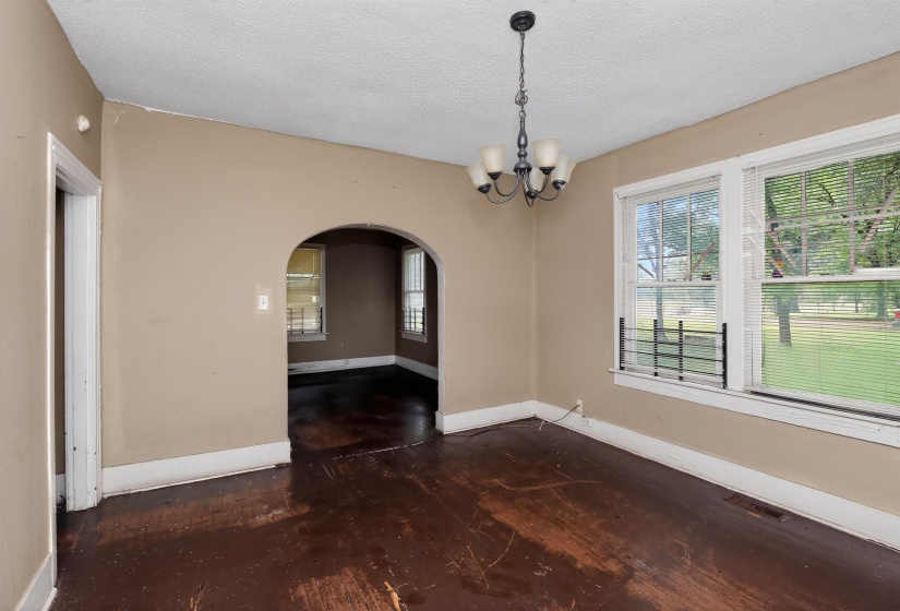 Room with wood-finish flooring, an arched doorway, and a multi-light chandelier