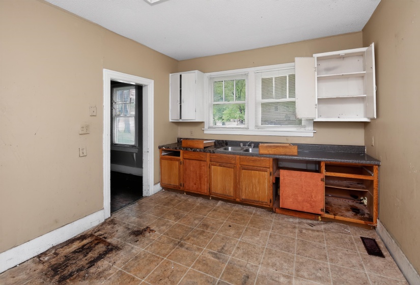 Kitchen area featuring a double window, dual basin sink, and a combination of upper and lower cabinetry