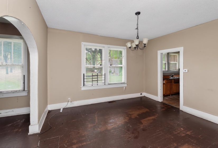 Spacious interior room featuring multiple windows, a ceiling-mounted light fixture, and an arched doorway