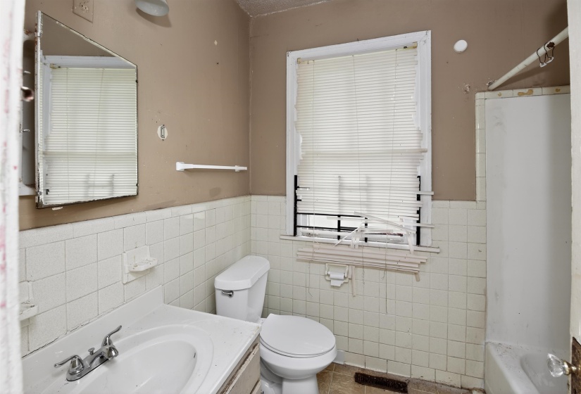 Bathroom featuring a window, white wall tiling, a toilet, a vanity with an integrated sink, and a mirrored medicine cabinet