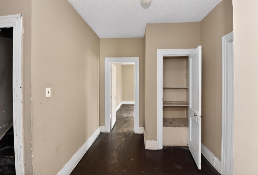 Interior hallway featuring dark wood-finish flooring, neutral-toned walls, and white trim