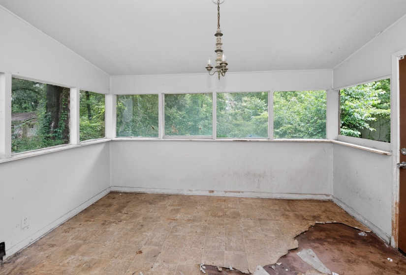 Room featuring extensive window placement, a ceiling-mounted light fixture, and a brown paneled door