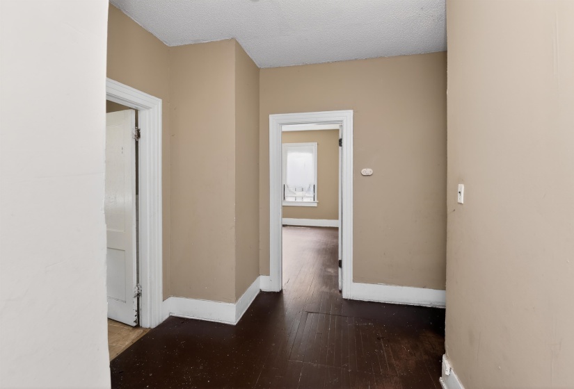 Hallway featuring wood-finish flooring, neutral wall paint, white trim, and multiple doorways