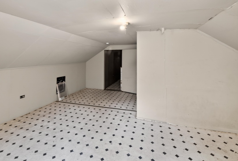 Attic space featuring sloped ceilings, patterned tile flooring, and white painted walls